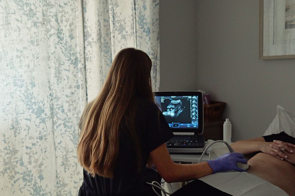 Summer performing a keepsake ultrasound with the baby visible on the monitor